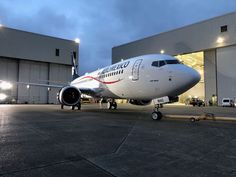 an airplane is parked in front of a hangar at night, with lights on the windows