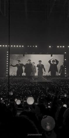 a group of people standing on top of a stage in front of an audience at a concert