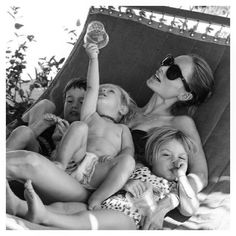 three women and two children are laying in a hammock with their arms up