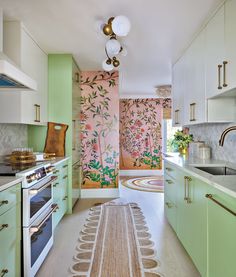 a kitchen with green cabinets and white counter tops, an area rug on the floor