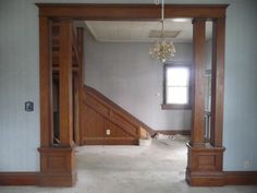 an empty living room with stairs and chandelier