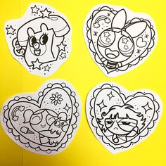 four heart shaped stickers on a yellow background with the faces of cartoon characters in black and white