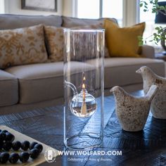 a glass vase with a candle inside sitting on a table in front of a couch