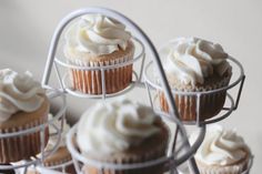 several cupcakes with white frosting sitting on a wire rack