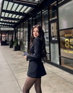 a woman in tights and heels is standing on the sidewalk with her legs crossed