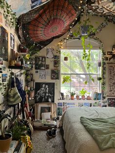 a bedroom with lots of plants and pictures on the wall above the bed, along with an umbrella hanging from the ceiling