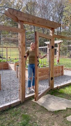 a woman standing in front of a chicken coop with her arms out and hands on the door