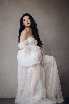 a woman in a white dress posing for the camera with her hand on her hip