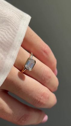 a woman's hand wearing a gold ring with an aquamarine colored stone on it