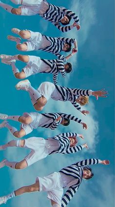 four women in striped shirts and white pants are posing for the camera with their hands up