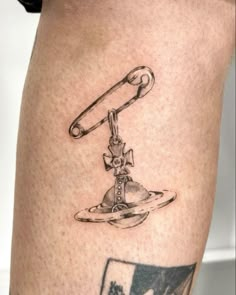 a tattoo on the leg of a man with a hook and scissors attached to it