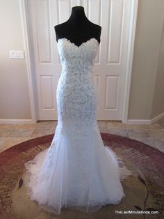 a white wedding dress on display in front of a door with a black mannequin