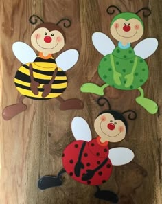 three paper cut out of different types of bugs and ladybugs on a wooden surface