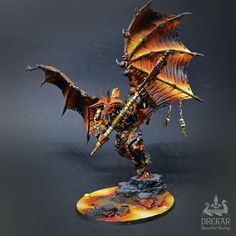 a miniature model of a dragon with yellow wings and orange body, on a black background