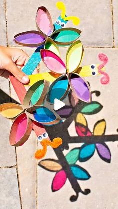 a child's hand is holding a paper flower