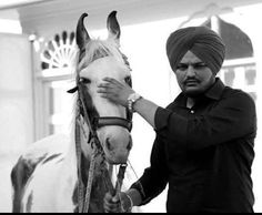 a man standing next to a horse with a turban on it's head