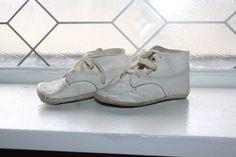 a pair of white shoes sitting on top of a window sill next to a wall