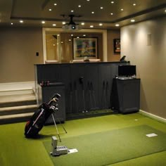 a golf bag sitting on top of a green floor next to a tv and some stairs