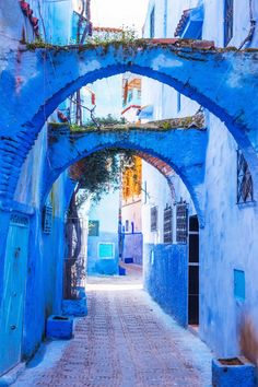 an alley way with blue walls and arched archways on both sides, leading into the distance