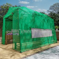 a small green house sitting on top of a wooden deck