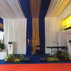 the stage is set up for an event with white drapes and blue carpeting