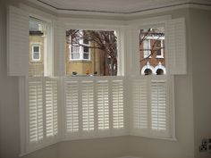 two windows with white shutters in a room