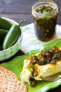 a green plate topped with food next to a bowl of pickles