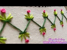 some pink and green flowers are on a piece of fabric with thread in the middle