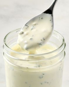 a spoon full of yogurt and some sort of sauce in a glass jar