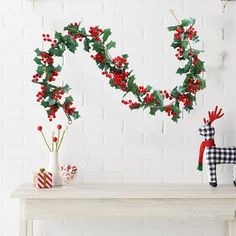 two christmas decorations on a table next to a white brick wall with red and green accents