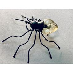 a metal insect sculpture sitting on top of a white table