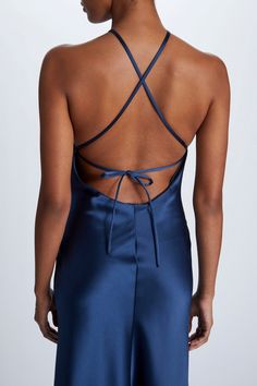 the back of a woman wearing a blue satin jumpsuit with an open cross - back