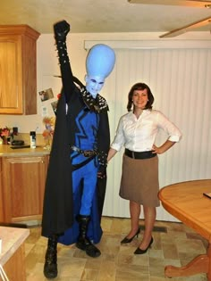 two women standing next to each other in a kitchen with an alien statue on the counter