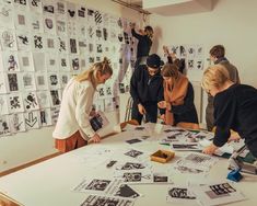 several people standing around a table covered in black and white pictures, with one person pointing at something on the table