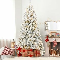 a white christmas tree with red and gold decorations in a living room decorated for the holidays