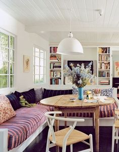 a living room filled with lots of furniture and bookshelves next to a dining table