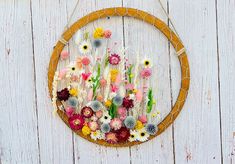 a wreath with flowers hanging on the side of a wooden wall in front of a white fence