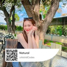 a woman sitting at a table in front of a tree with qr code on it