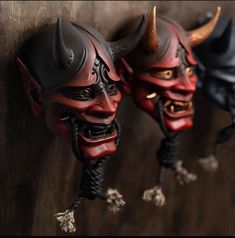 two red and black masks with horns hanging on a wall