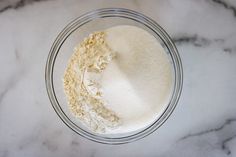 a glass bowl filled with flour on top of a marble counter