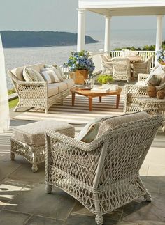 an outdoor living area with wicker furniture and water in the backgroung