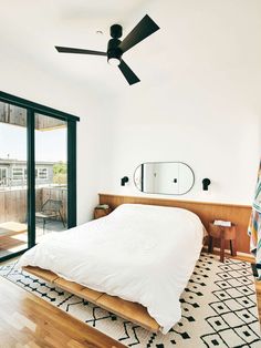 a bedroom with a bed, ceiling fan and sliding glass doors