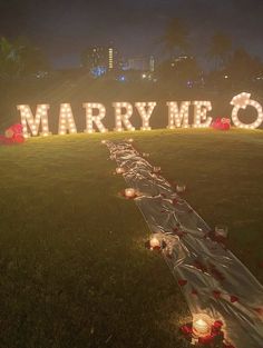 many candles are placed on the grass near a sign that says marry me o'clock