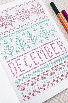 a cross stitch pattern next to two crayons