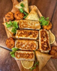 some food that is on top of a wooden tray with lemon slices and garnishes