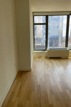 an empty room with hardwood floors and large windows