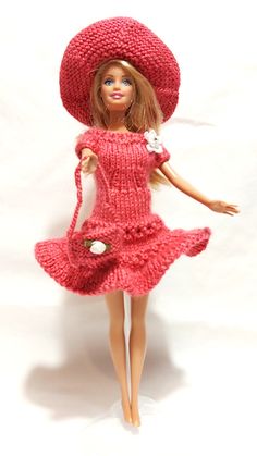 a barbie doll wearing a red knitted dress and hat holding a small white cat