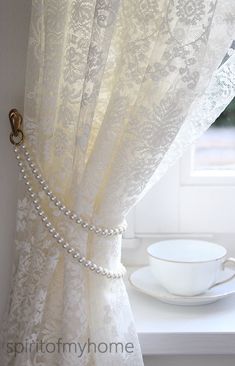 the curtain is open and ready to be hung in front of the window with pearls on it