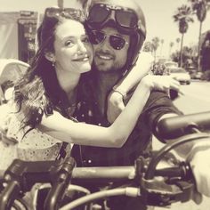 a man and woman on a motorcycle posing for the camera with their arms around each other