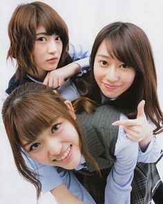 three young women posing for the camera with one pointing at the camera and the other holding her hand up